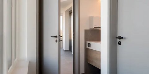 Nahaufnahme einer Holztür mit einem silbernen, gebogenen Türgriff und einem ovalen Schlüsselloch darunter.